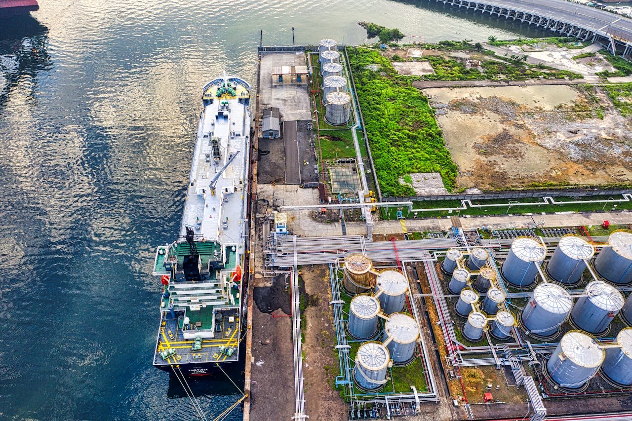 Aerial view of a ship docking at an industrial port with storage tanks in North Jakarta.