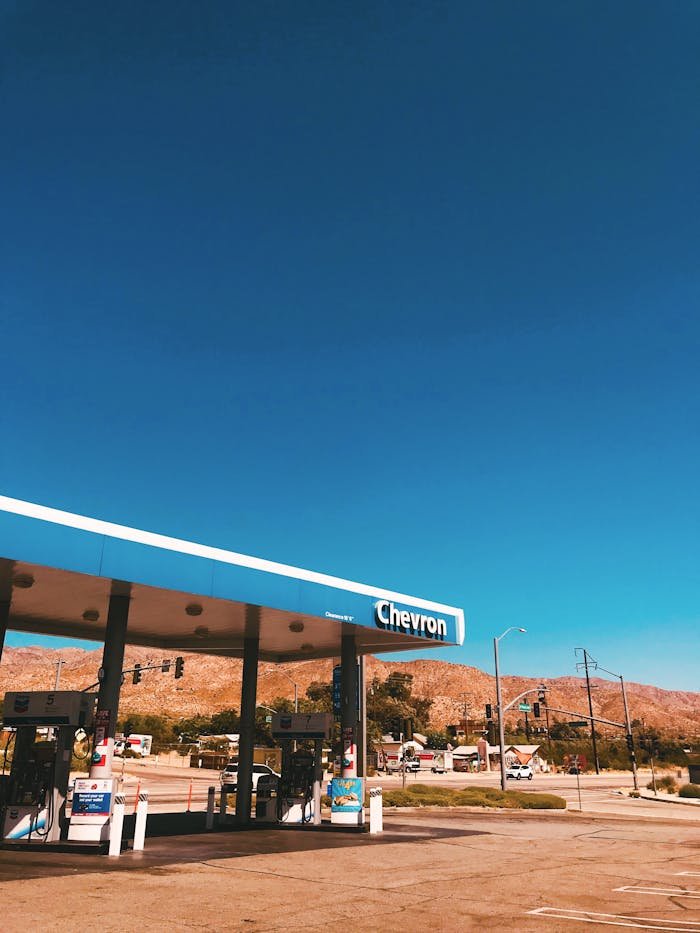 A Chevron gas station with mountains in the background under a clear blue sky in California, USA.